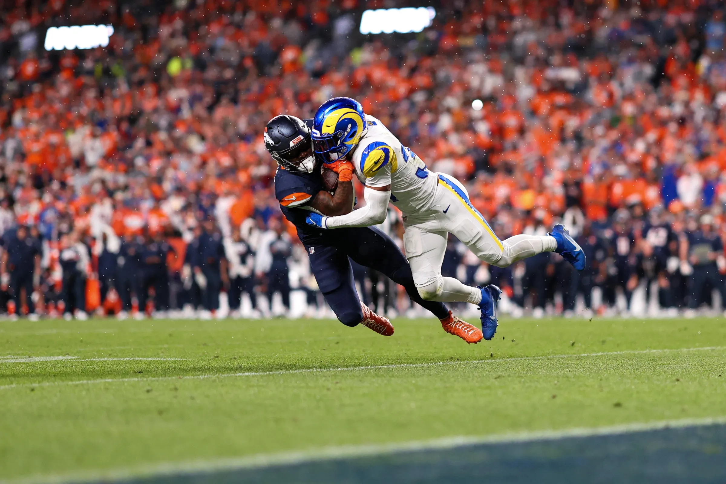 DENVER, COLORADO - SEPTEMBER 27: RJ Harvey #12 of the Denver Broncos is tackled by Quentin Lake #37 of the Los Angeles Rams during the third quarter of the game at Empower Field at Mile High on September 27, 2026 in Denver, Colorado. (Photo by Brooke Sutton/Getty Images)